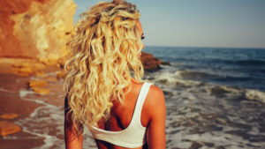 Blonde curly hair tan girl watching ocean