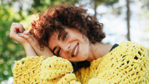 Close-up outdoor portrait of attractive young woman with curly hair and smiling.
